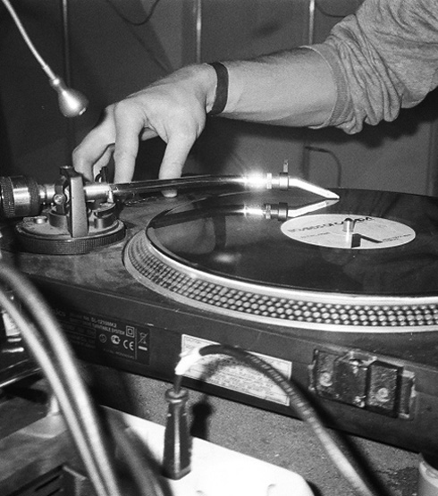Closeup of a DJ's arm operating a turn table