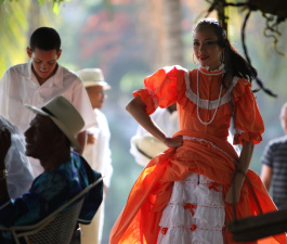A hispanic woman dancing in a red dress.